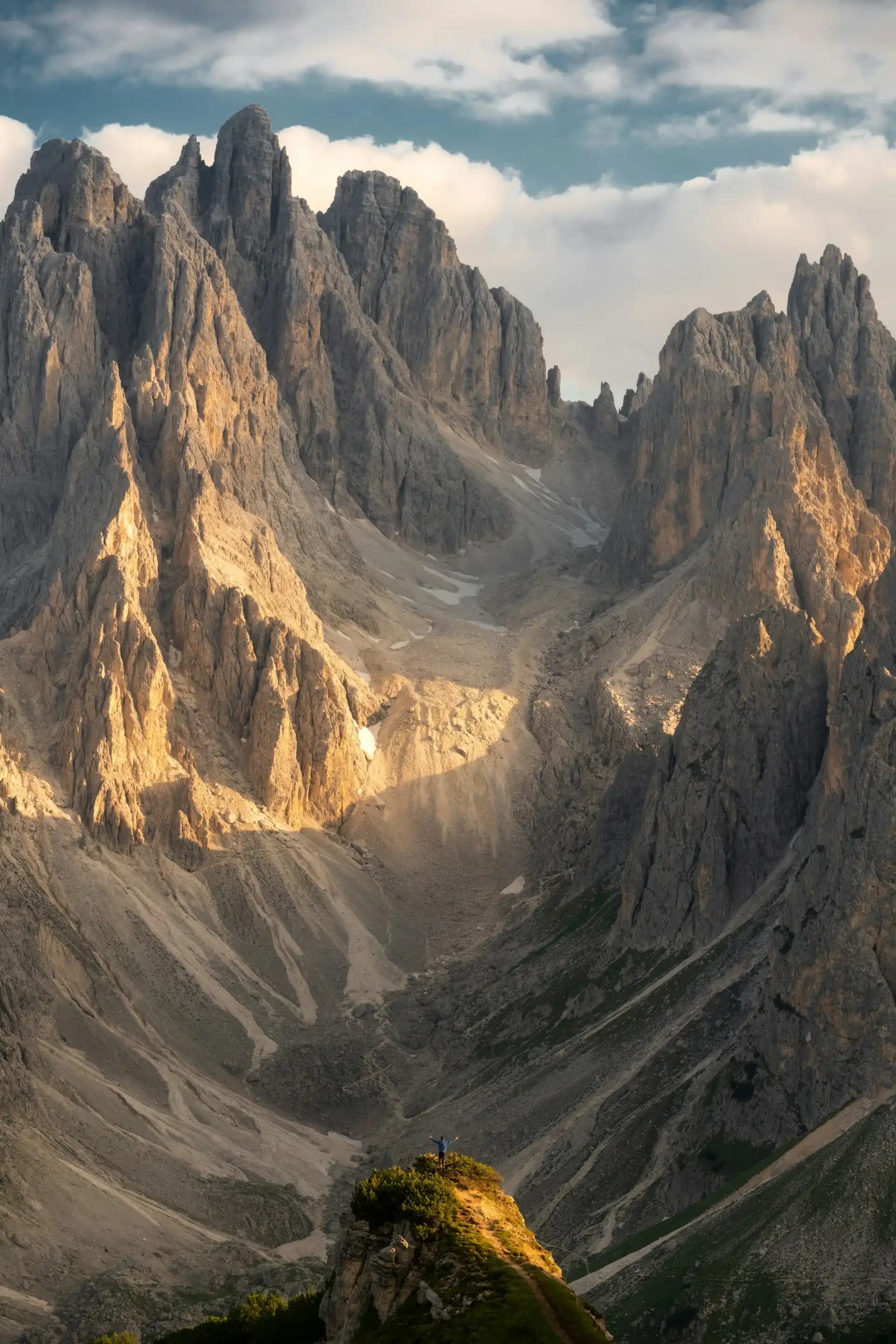 Limestone peaks in the Dolomites with a hiker on a ridge overlook